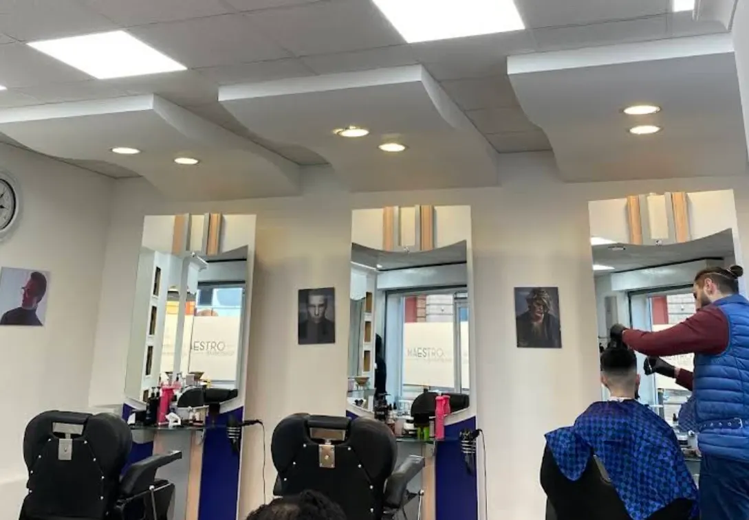 Inside Maestro Barbershop: three black chairs, mirrors and a barber at work