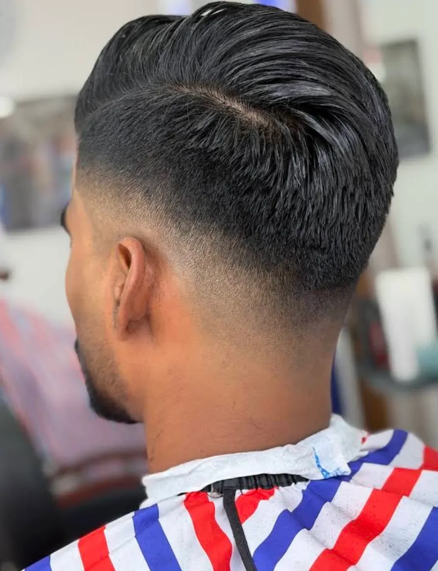 Low skin fade with a slicked back top, seen from behind